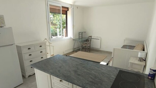 A compact kitchen with white cabinets, a black countertop, and a built-in stove.