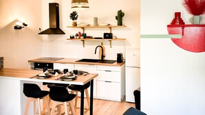 A modern kitchen with a central island, black chairs, a dining table, and a hanging woven light fixture. - Apartment 5 min from Disney (Montévrain)