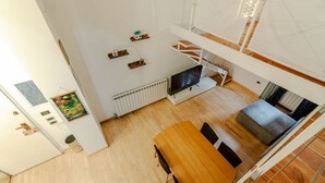 A modern interior with a dining area, a TV, and a staircase. - GuestHost - Comfortable Loft Apartment Turin (Turin)