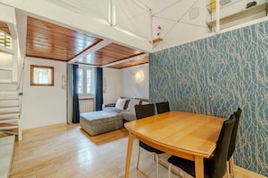 Un salon moderne avec une table à manger en bois, un canapé et un mur décoré d’un motif.