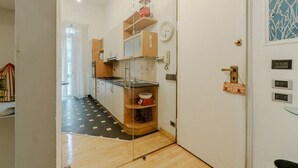 A compact kitchen with a stove, cabinets, and a clock on the wall. - GuestHost - Comfortable Loft Apartment Turin (Turin)