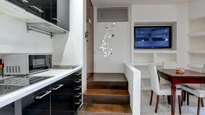A modern kitchen with a microwave, a built-in oven, and a dining area with a wooden table and white chairs.