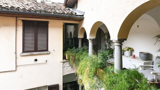 A traditional courtyard with arches, a tiled roof, and potted plants.
