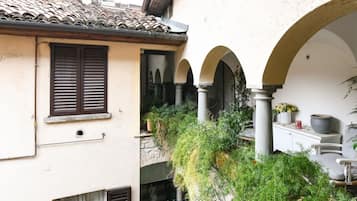 A traditional courtyard with arches, a tiled roof, and potted plants.