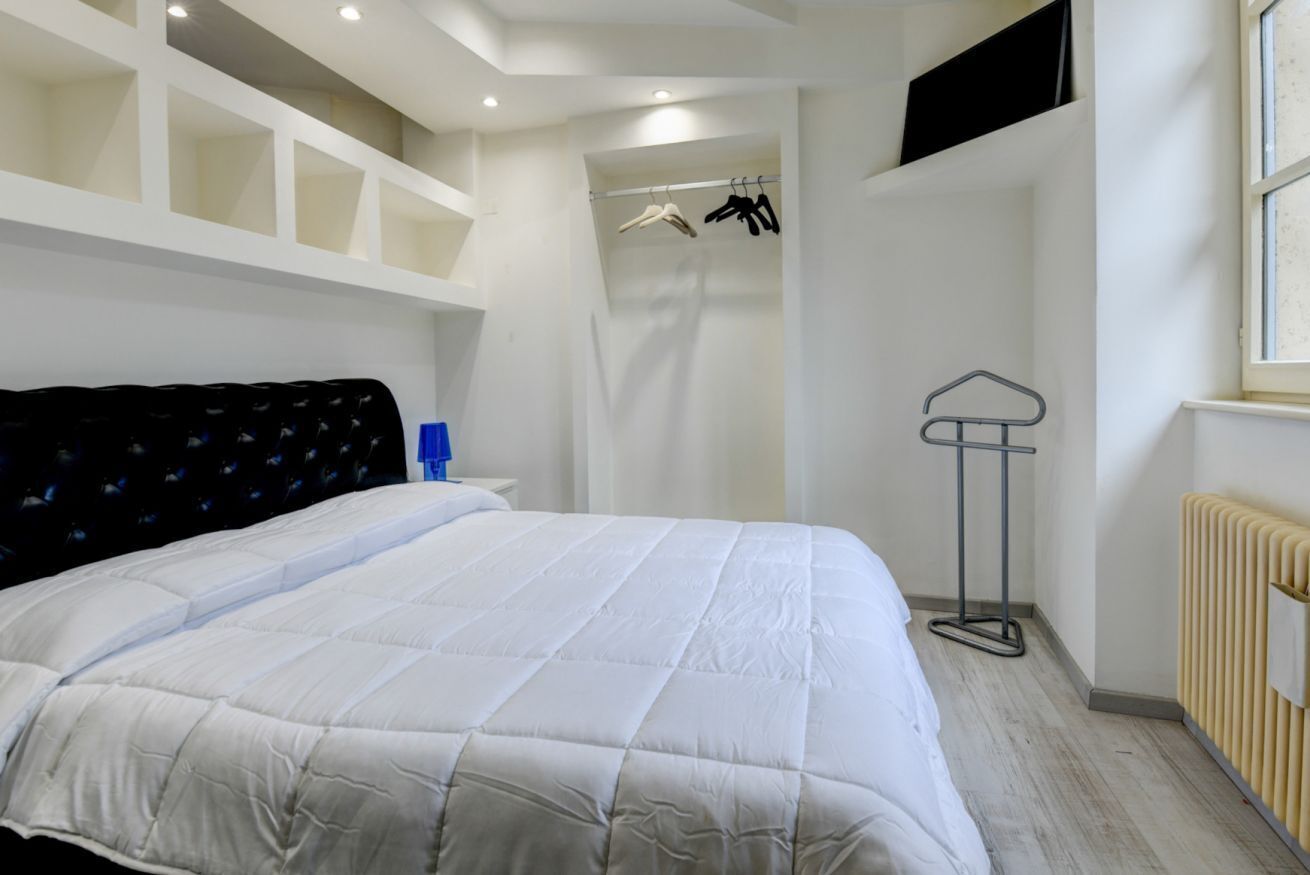 Une chambre à coucher comprenant un lit, une armoire, un radiateur et un porte-vêtements.