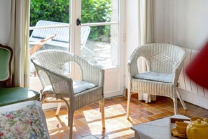 A room with wicker chairs, a green sofa, and a tiled floor.