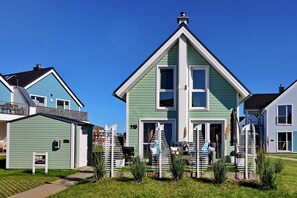 Una hilera de casas con un estilo arquitectónico particular, que destaca un tejado a dos aguas y una entrada central.