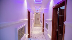 Un couloir doté d’un sol en marbre, de portes en bois et d’un éclairage violet.