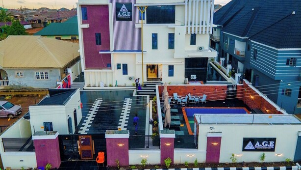 Un hôtel moderne doté d’une terrasse sur le toit, de plusieurs étages et arborant un logo A.G.E. bien visible.
