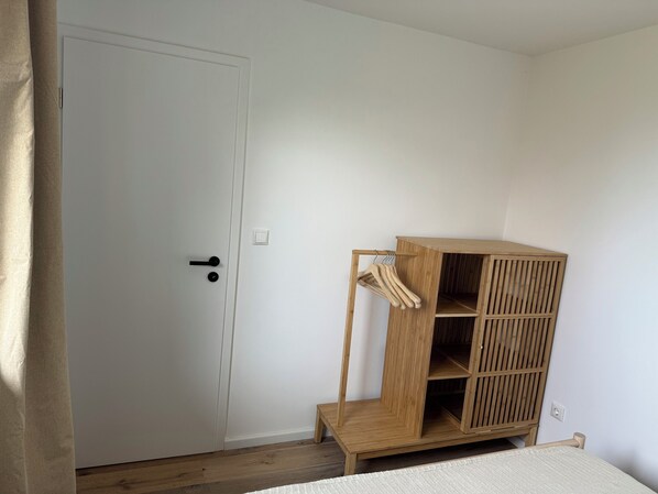 A room with a wooden wardrobe, a white door, and a wooden floor.