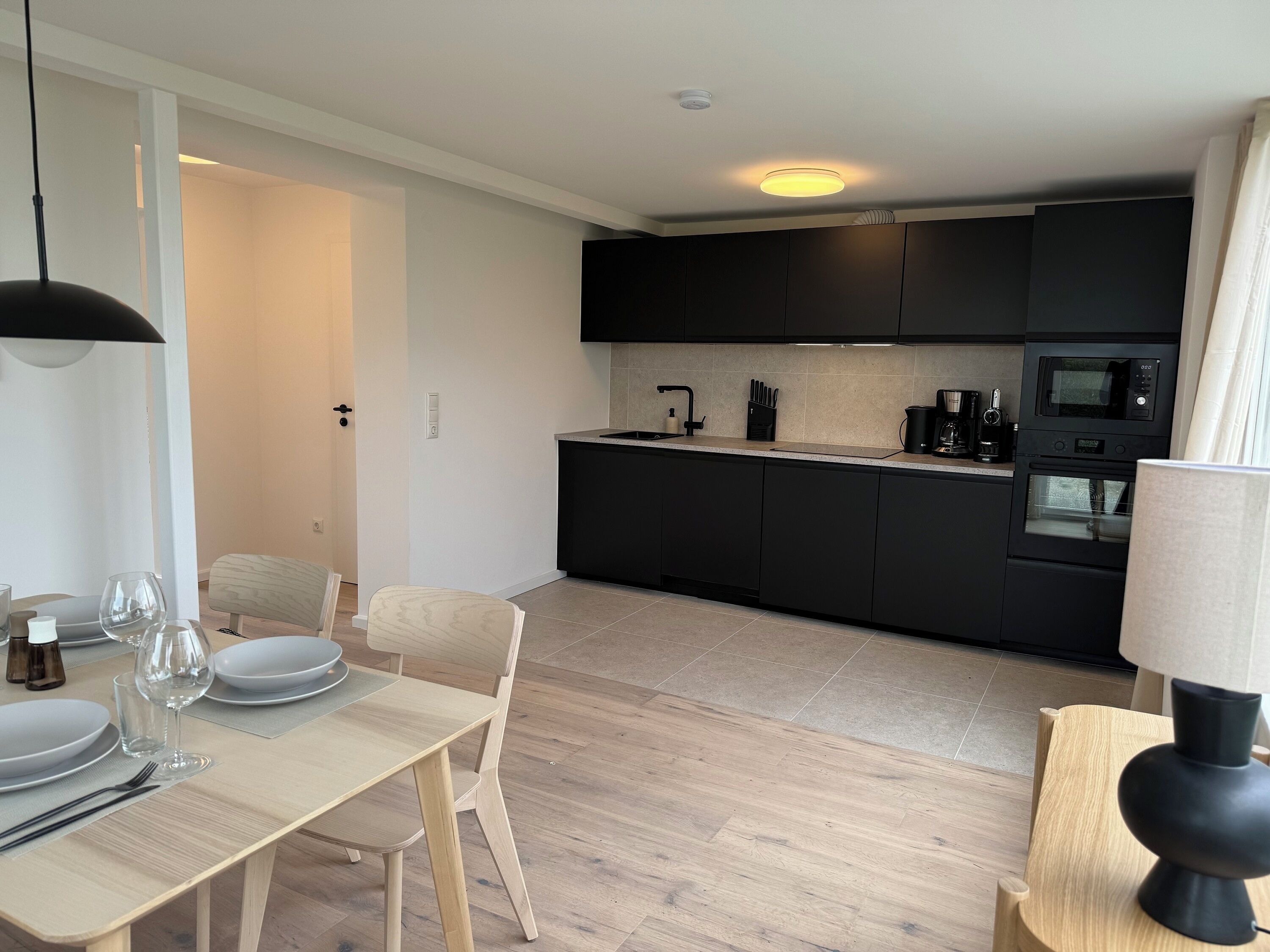 A modern kitchen with black cabinets, a built-in microwave, and a coffee maker.