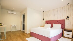 Une chambre à coucher avec un grand lit, une table de chevet, une commode, un petit bureau et une armoire.