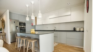 Une cuisine moderne dotée d’un îlot central, de tabourets de bar et de luminaires suspendus.