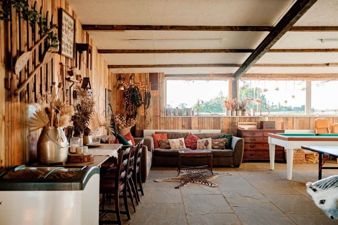Un espacio de sala acogedor con pared de madera, un sofá, una mesita de centro y una mesa de billar.
