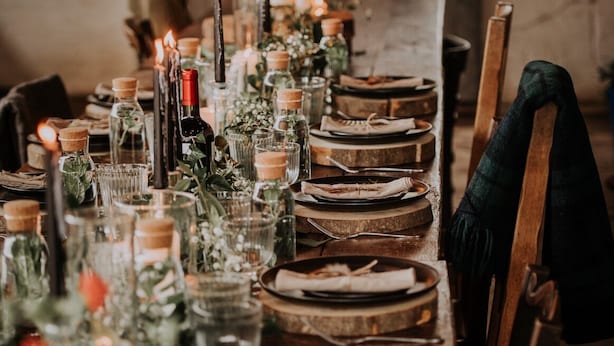 A long dining table set with candles, glass bottles, and plates.