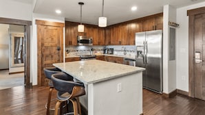 A modern kitchen with wooden cabinets, stainless steel appliances, and a central island with bar stools. - 500 ft from Pickleball | Private Gondola Access | Hot Tubs & Fitness Center (Steamboat Springs)
