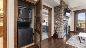 A modern kitchen with a built-in oven and microwave, a stone fireplace, and a dining area with a table and chairs. - 500 ft from Pickleball | Private Gondola Access | Hot Tubs & Fitness Center (Steamboat Springs)