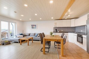 A modern kitchen with white cabinets, a wooden dining table, and a grey sofa. - Apartment An der Kapf, 80 sqm, Garden and Balcony, Max. 4 Guests, 4 Stars - DTV Certified (Münsingen)
