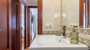 Un baño con un lavamanos grande, un espejo y una botella de perfume.