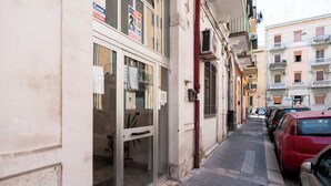 A narrow street with parked cars and a building with a glass door and windows. - Rifugio Pugliese by Wonderful Italy (Bari)
