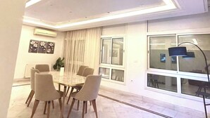 A dining area with a round table, six chairs, and a modern ceiling light fixture. - Luxury Stay with Panoramic Sea Views, Tourist zone (Sousse)