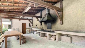 An outdoor kitchen area with a wooden table, a built-in grill, and a stone wall.