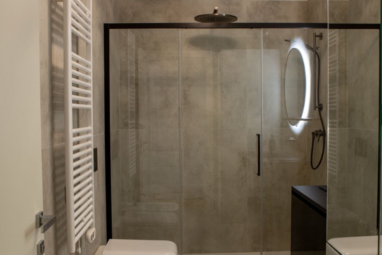 A modern bathroom with a glass-enclosed shower, a white toilet, and a glass shower door.