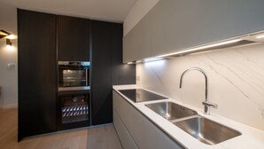 A modern kitchen with built-in appliances, a double sink, and under-cabinet lighting.