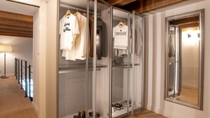 A walk-in closet with hanging clothes, a mirror, and shoes on shelves.