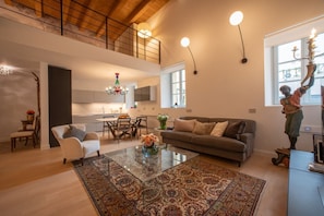 A spacious living area with a high ceiling, a dining table, a sofa, and a decorative statue.