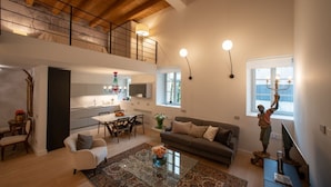 A spacious living area with a high ceiling, a dining area, a kitchen, and a balcony.