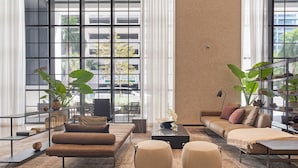 A modern living room with a sofa, ottomans, a coffee table, and large windows offering a view of the outside. - Luxury Corner 2bdcity & Bay Viewsamazing Sunsets (Miami)
