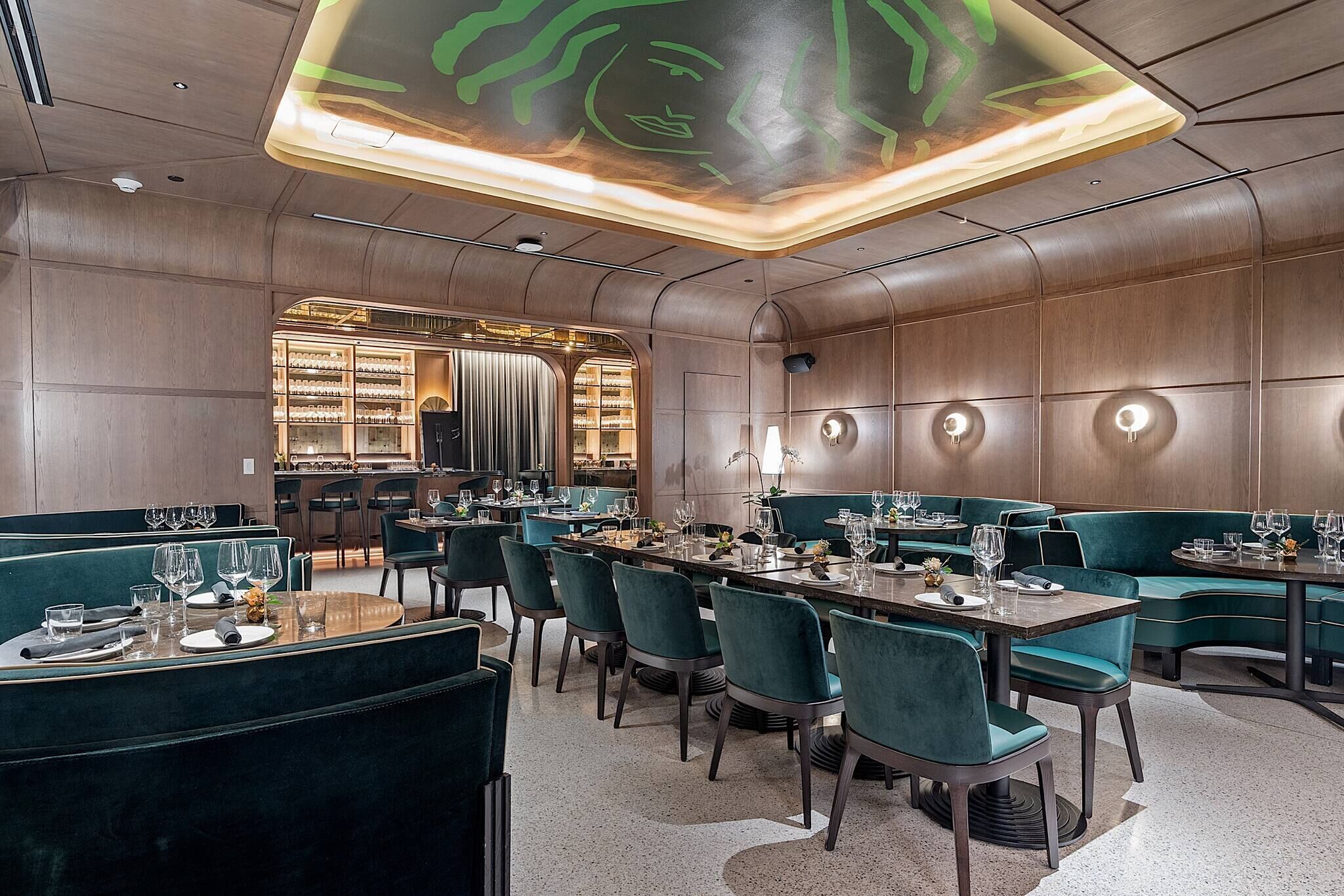 A modern restaurant with booths and tables, a bar area, and a unique ceiling design.