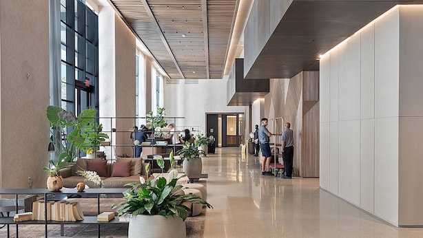 Eine großzügige Lobby mit modernem Design, ausgestattet mit einer langen Rezeption, gemütlichen Sitzbereichen und großen Kübelpflanzen.