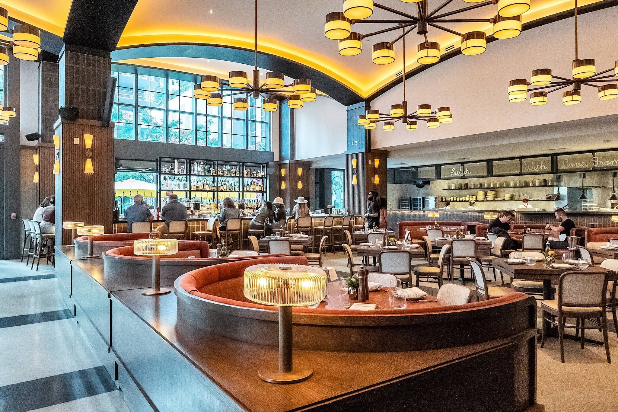 Ein geräumiges Restaurant mit hohen Decken, mehreren Essbereichen und einer Bar.