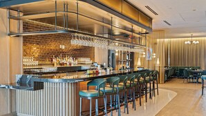 A modern bar area with a long counter, multiple bar stools, and a variety of bottles and glasses. - Luxury 1BR Penthouse, Bay & City Views Downtown (Miami)