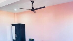 A bedroom with a bed, a desk, a chair, and a ceiling fan. - Ocean Paradise Beach Homestay (Karwar)