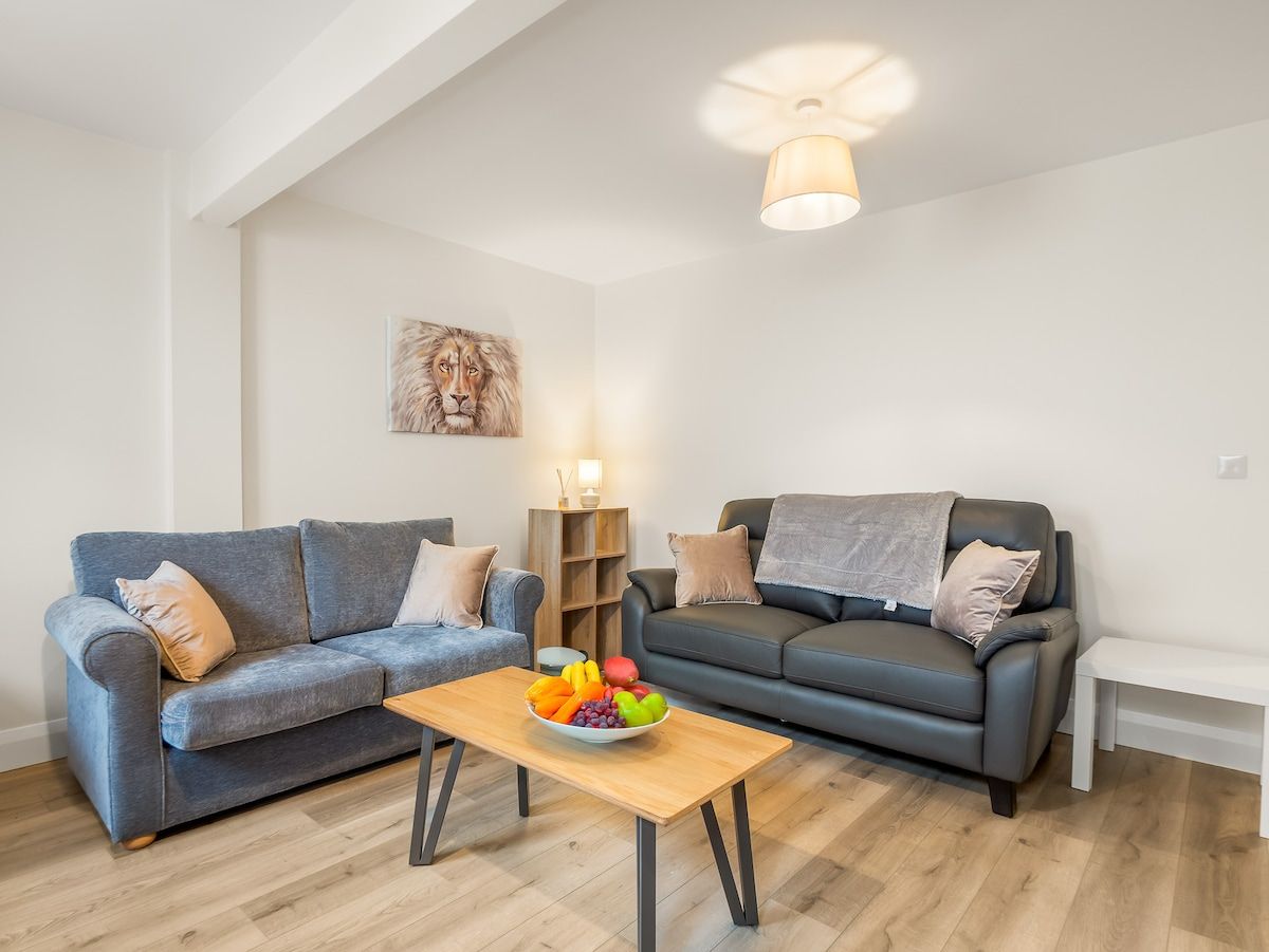 A living room with two sofas, a coffee table with fruit, and a lamp.