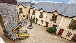 A courtyard with a stone staircase, a central fountain, and a seating area. - 17 Clifden Court getaway with free parking (Clifden)