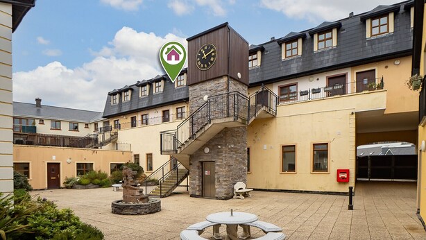 A courtyard with a stone fountain, a clock tower, and a sign indicating a location. - 17 Clifden Court getaway with free parking (Clifden)