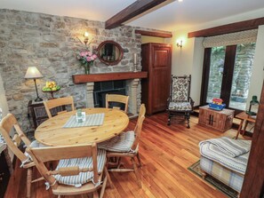 A cozy dining area with a stone wall, wooden furniture, and a fireplace. - Bradshaw House (Hope Valley)