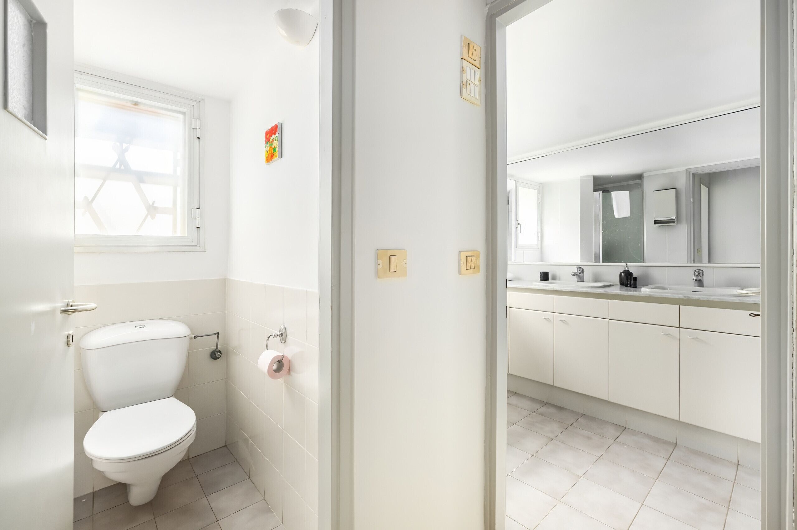 Een kleine, schone badkamer met toilet, wastafel en spiegel.