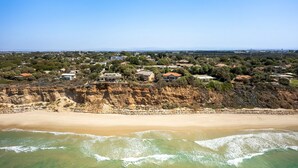 Una zona costera con playa arenosa y un acantilado rocoso.