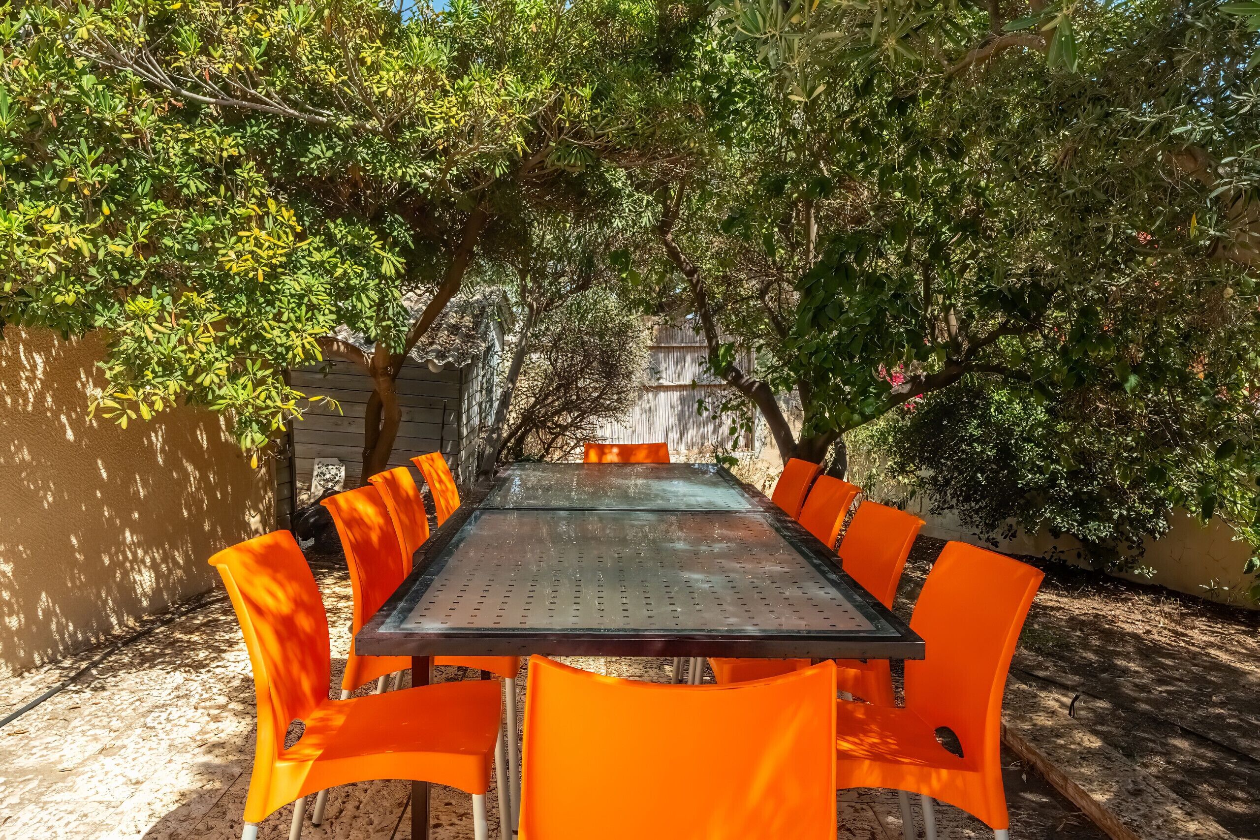 A rectangular metal table with a glass top surrounded by six orange chairs.