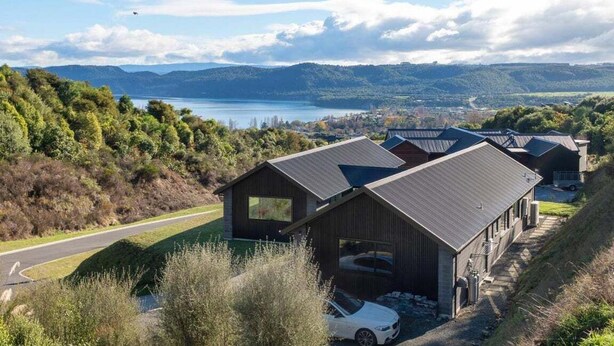 Um edifício moderno com uma garagem espaçosa, cercado por vegetação exuberante e vista para um lago.