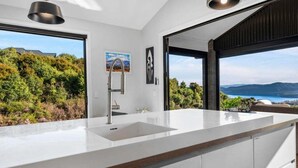 Cozinha moderna com uma ilha grande, vista para o mar e área de jantar com vista.