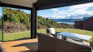 Um interior moderno com uma grande janela de vidro, mobiliário de vime e vista para uma paisagem natural.