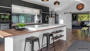 Cozinha moderna com ilha central, armários pretos e iluminação pendente.