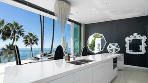Una cucina moderna con una grande isola, un lampadario e vista sull'oceano.