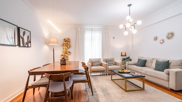 Un salon moderne avec une table à manger en bois, deux fauteuils, un canapé et une table basse.